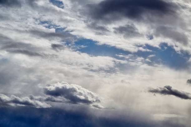 Sunlight filtering through stratus clouds in soft focus, with a blurred sky background, indicating improving weather and a change in weather during autumn.