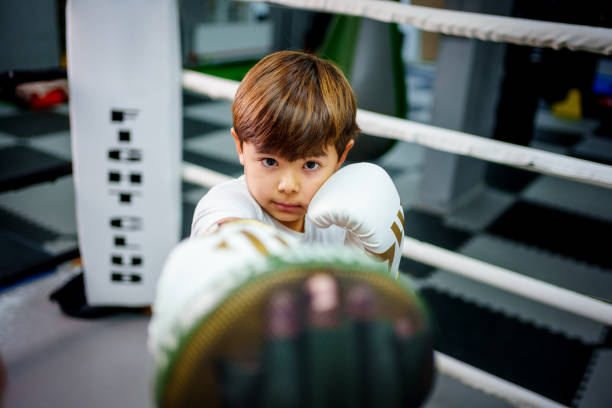 istock Focused young boy practicing boxing with his trainer inside a boxing ring in a gym. 2183734474