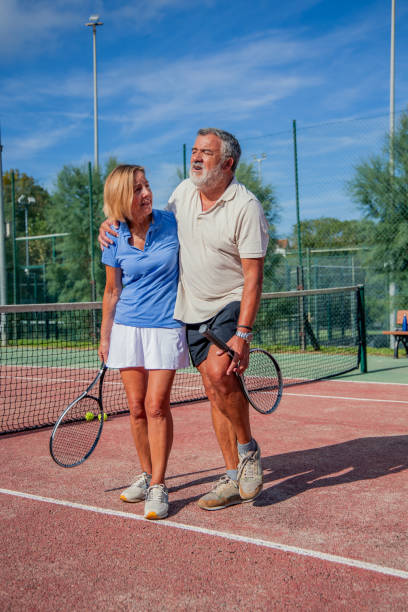 istock vertical elderly tennis player with knee injury leaning on partner while exiting court 2183735732