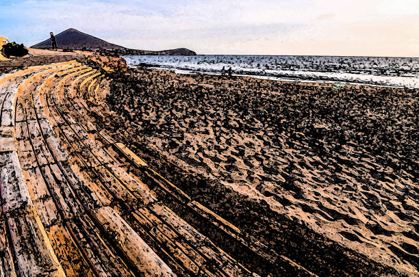 A beach with a wooden boardwalk and a person walking on it. The beach is empty and the sky is cloudy