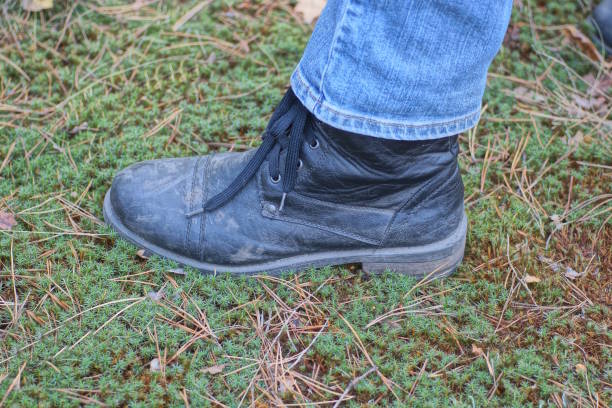 istock a man leg in a black leather boot and blue jeans stands on green moss 2183740385