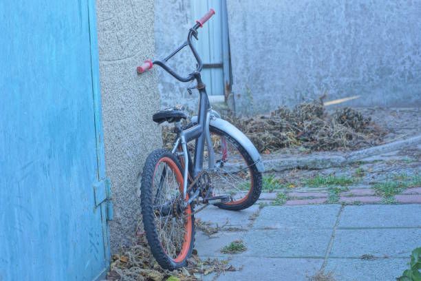 istock one old black bicycle stands near a gray concrete wall 2183740545