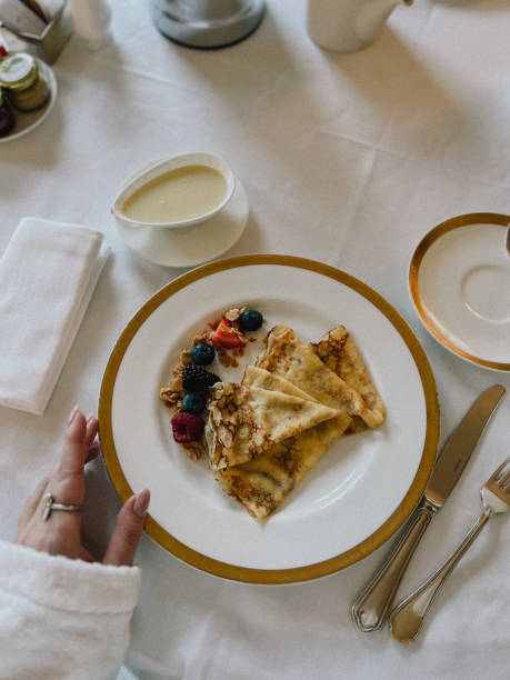 Elegant breakfast scene with pancakes, berries, and fine tableware