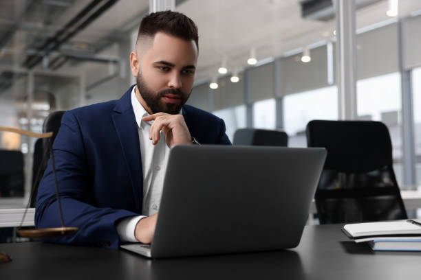istock Serious lawyer working with laptop at table in office 2183752397