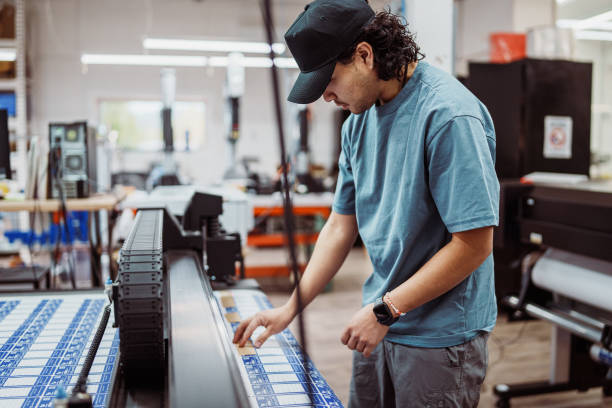 istock Male worker operating large format printer and paper cutter in factory 2183753314