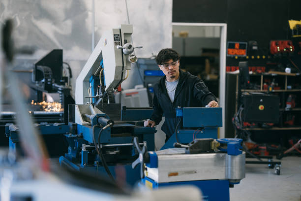 Engineer operating metal engraver in factory A man operates a CNC machine which engraves metal while working in a manufacturing and fabrication facility. laser cutting metal stock pictures, royalty-free photos & images