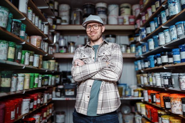 istock Man standing in workshop storage room surrounded by cans of paint 2183753401