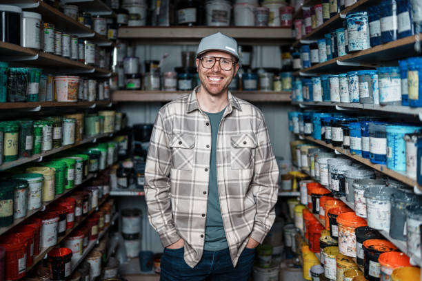 Man standing in workshop storage room surrounded by cans of paint