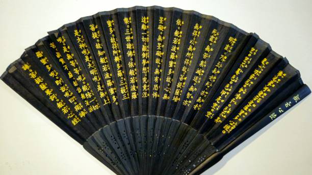 istock Black folding silk fan with gold Chinese characters written on it. The fan is spread open, displaying the text clearly. 2183755270