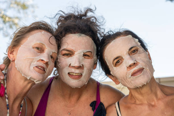 Portrait of three women outdoors with collagen mask on their faces looking at the camera.