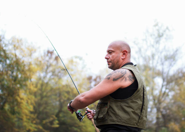 Fisherman with rod spinning reel on the river bank catching a fish. Copy space. Close up