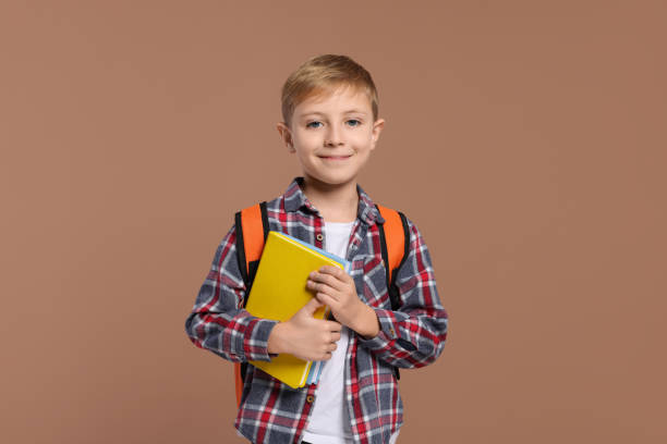 istock Happy schoolboy with backpack and books on brown background 2183761677
