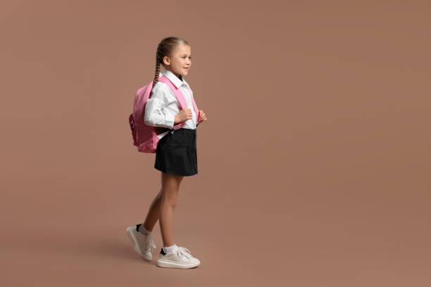 istock Happy schoolgirl with backpack on brown background, space for text 2183761687