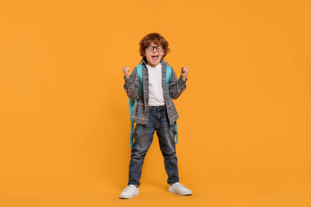 istock Emotional schoolboy with backpack on orange background 2183761844