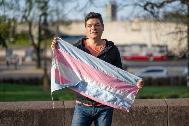 istock Gay man holding transgender flag looking at the camera 2183768178