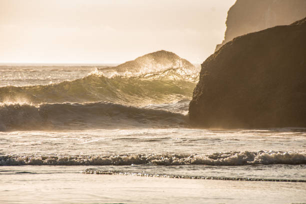 The powerful waves crashing on a sea stack in Bandon, Oregon with the sun setting behind.