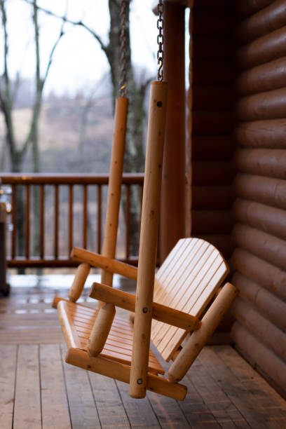 istock Log cabin wooden swing hangs from chains on a rustic rural porch 2183770649