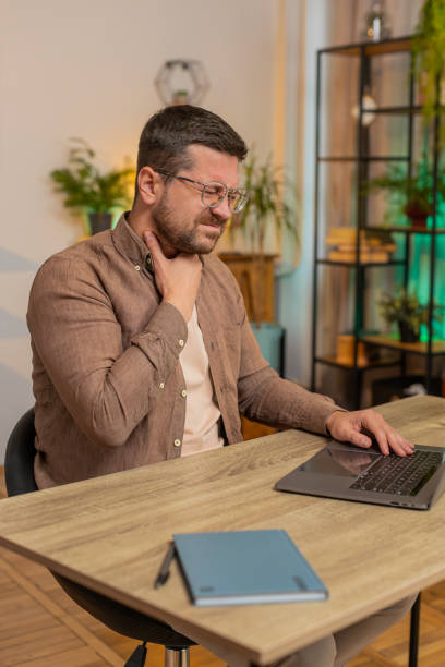 istock Sick man freelancer feeling unwell suffering from sore throat touches chest while coughing at home 2183772043