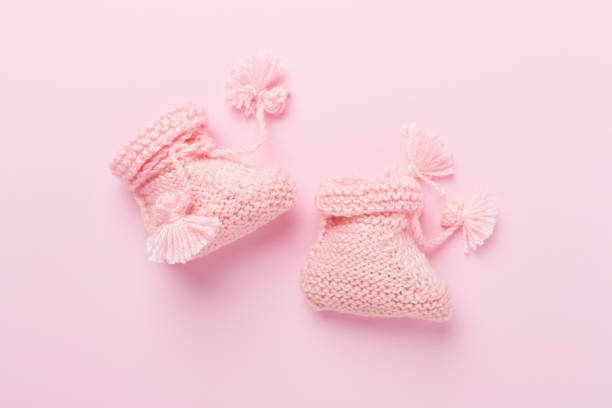 istock Pink baby booties on color background, top view 2183773101