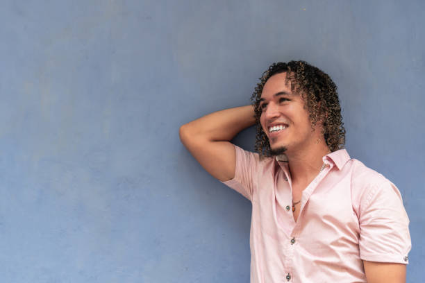 istock Hispanic man smiling and leaning against blue wall 2183789631