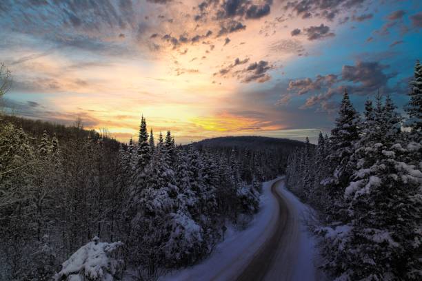 istock Scenic winter road winding through a snow-covered forest at sunset 2183801792