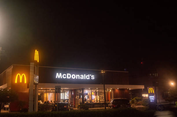 A brightly lit McDonald s restaurant at night with visible signage and a drive thru, showcasing the iconic golden arches, Indonesia, 4 November 2024.