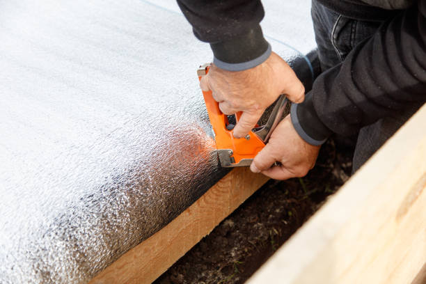 istock A man is using a staple gun to attach a piece of insulation to a wooden board 2183807513