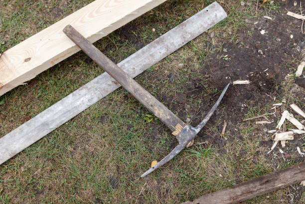 A rusty pickaxe is laying on the grass next to a wooden plank. The scene is somewhat eerie and abandoned, with the pickaxe and plank being the only objects visible