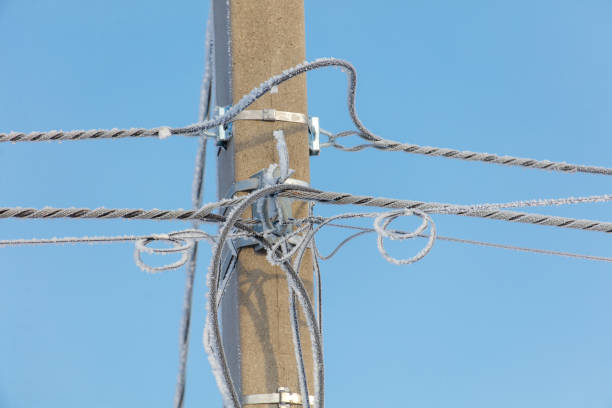 A pole with wires on it is covered in ice. Concept of cold and isolation, as the wires are frozen and the pole is bare