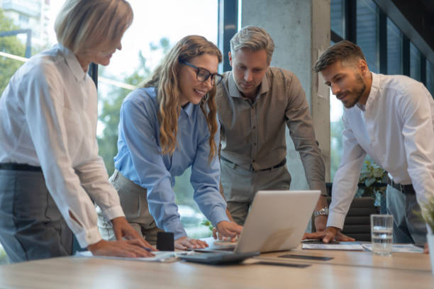 istock Happy four business people executive team working at laptop having discussion at office meeting showing financial project 2183817821