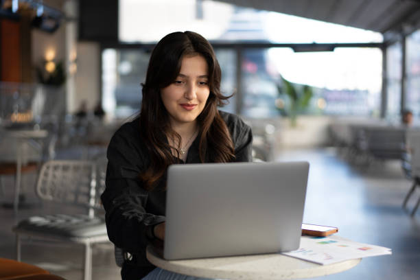 istock Smiling woman working on laptop in cafe 2183822909