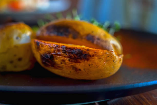 Baked spicy potatoes on plate, close up. Selective focus. Horizontal image.