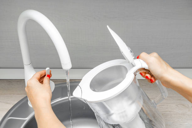istock housewife pouring water into water filter in kitchen. 2183831770