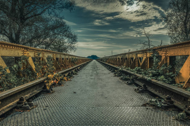 Old railroadtrack on a steel bridge with blue sky, clouds en tree