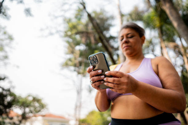 istock Woman using the mobile phone while walking at the park 2183837878