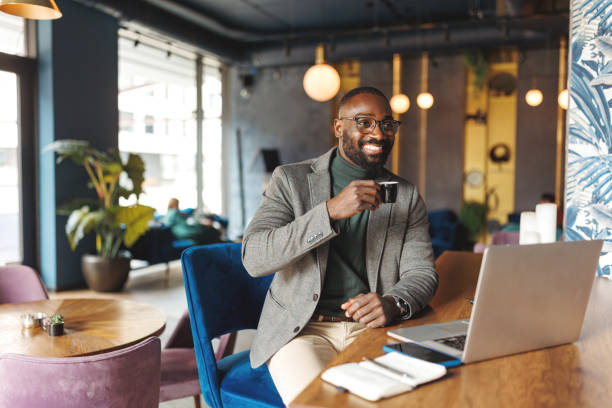 Man in cafe sipping espresso with laptop open