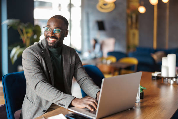 istock Smiling man works at laptop in contemporary cafe. 2183841379