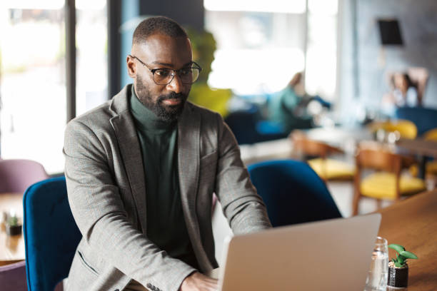 istock Man focused on laptop at cafe table in modern setting 2183841489