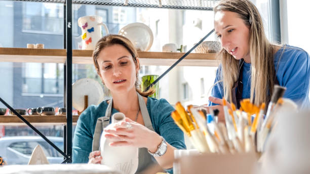 istock In an art studio with an environment adorned with artistic paintings in the background, two beautiful middle-aged women are happily drawing patterns on a clay ceramic vase they made together at a table 2183843349