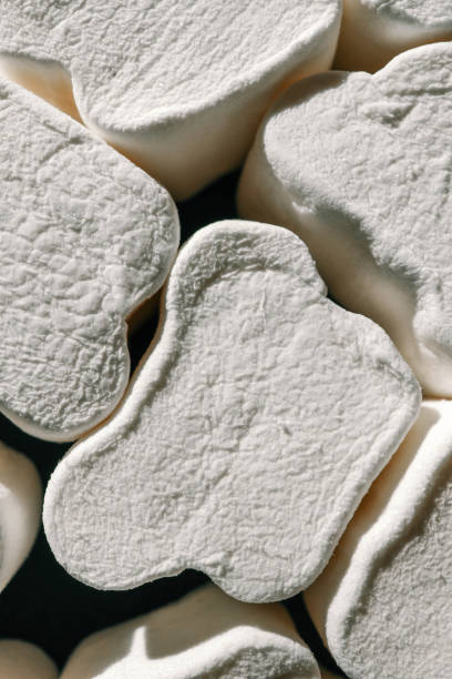 istock A close-up of fluffy, textured white marshmallows shaped like bones, arranged haphazardly under soft natural lighting. Shadows create depth, highlighting their unique surface details 2183845535