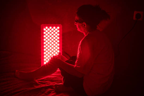 istock Senior woman treating sore leg with the red light therapy panel 2183852793