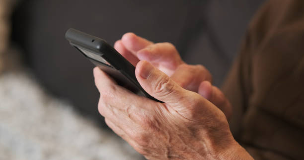 istock Hands of old man holding checking touching scrolling smartphone, close-up, side view 2183854408