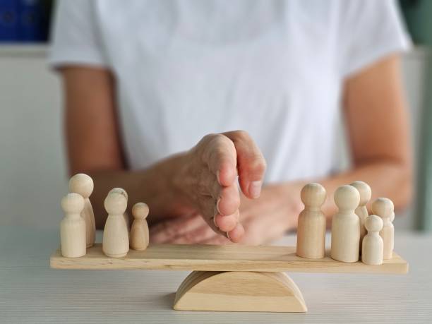 istock Balancing figurines on a wooden scale to represent equality and fairness during a team-building session 2183854668