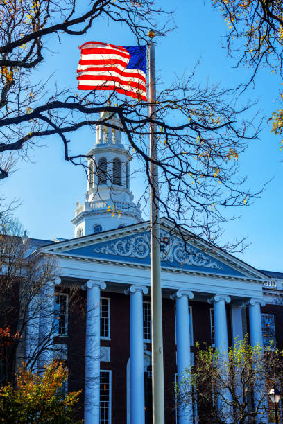 Boston, Massachusetts, USA - November 6, 2024: An American flag flying in front of the Baker Library on the Harvard Business School (HBS) campus. Dedicated in 1927 and named for George F. Baker, the benefactor who funded HBS's original campus. It is the largest business library in the world.