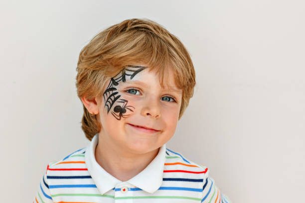 istock little kid boy with face painted with a spider web, Activity for kids on birthday celebration part, face painting, fun and happiness 2183857063
