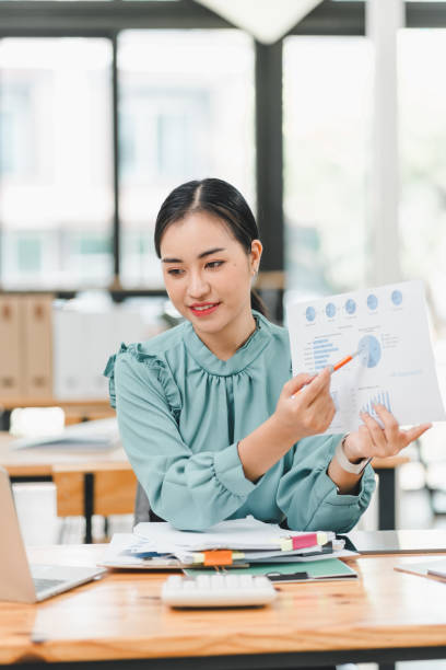 istock professional woman in green blouse presents data charts in modern office setting, showcasing her analytical skills and confidence. 2183858275