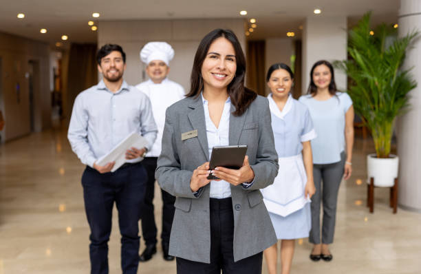 Hotel manager leading a group of employees at the lobby Happy Latin American hotel manager leading a group of employees at the lobby and looking at the camera smiling employee introduction stock pictures, royalty-free photos & images
