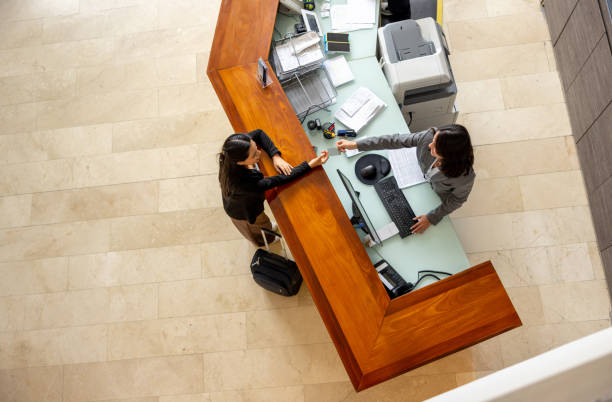 Receptionist handling cardkey to a guest while doing her check-in at a hotel - business travel concepts