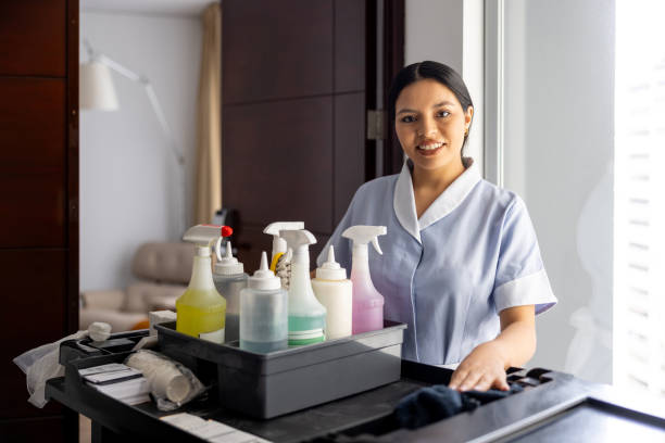 istock Housekeeper working at a hotel and smiling while pushing a cart with cleaning products 2183861993