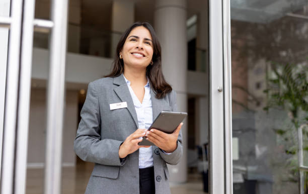istock Hostess holding a digital tablet and smiling at the door while working at a hotel 2183862015